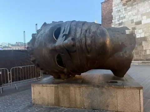 A monumental sculpted head lying on its side in Kraków