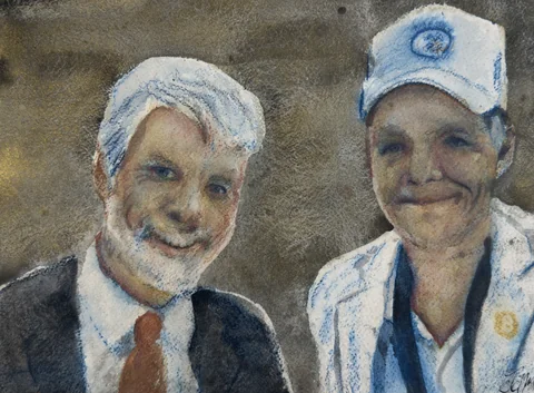 Two smiling men, one in a suit and one in a white cap
