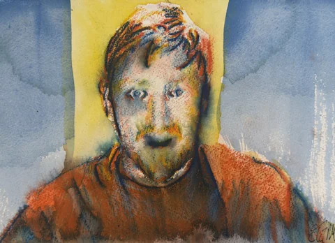 A bearded man with reddish hair and a rust-colored shirt