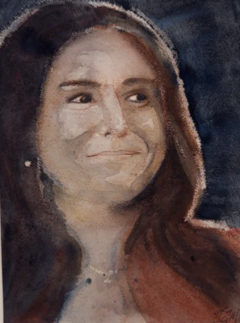 A smiling woman with dark hair against a dark background