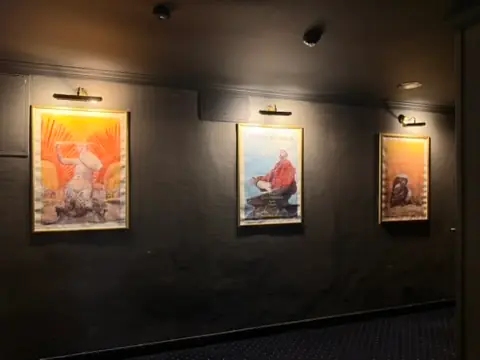 Three paintings displayed outside the Kinoteka theater for Bitcoin Film Festival