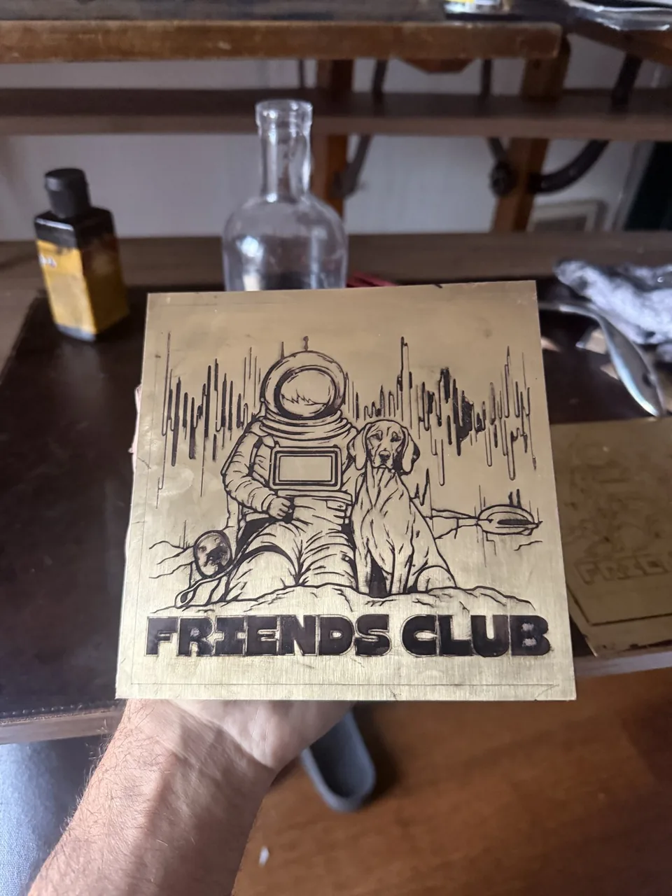 Finished Friends Club brass plate: the astronaut mascot in a raft with a dog and Billy Buff