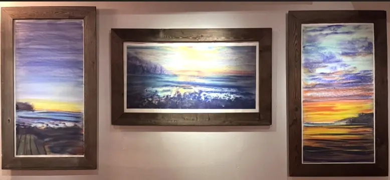 Three framed watercolor landscapes hanging side by side in a living room
