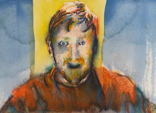 A bearded man with reddish hair and a rust-colored shirt