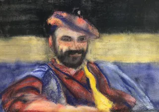 A bearded man in a colorful hat and scarf seated outdoors