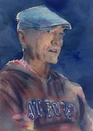 A man in a flat cap and Stanford sweatshirt against a deep blue background